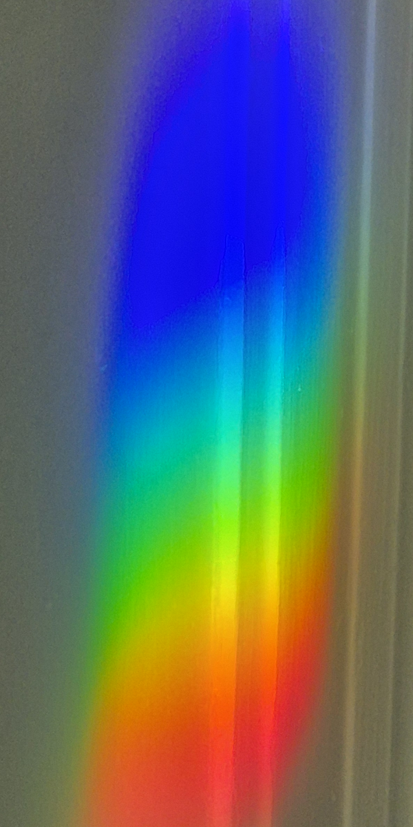 A SunRain prism suncatcher casting a stunning, tall vertical rainbow spectrum on a wall in a sunlit room